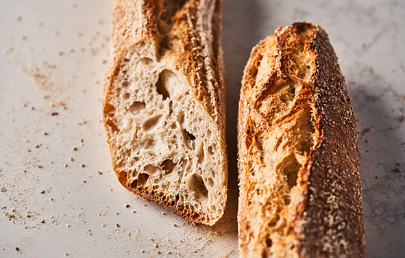 Baguette de pain posée sur une surface claire, avec une partie tranchée.