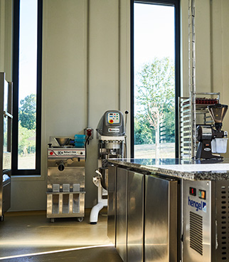 Équipement de production en inox installé dans un atelier, avec machines de transformation et grandes fenêtres laissant entrer la lumière naturelle.