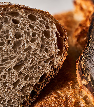 Close-up of a slice of bread showing an open, airy crumb, with a golden crust visible on the sides.