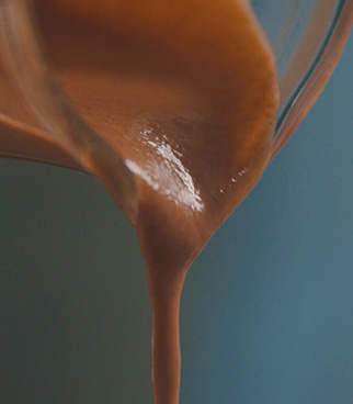 Levain liquide épais de couleur brune s’écoulant d’un récipient en verre incliné.