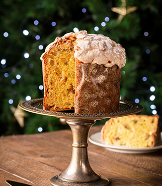 Panettone brioché présenté sur un présentoir, avec une part tranchée visible à l’arrière-plan.
