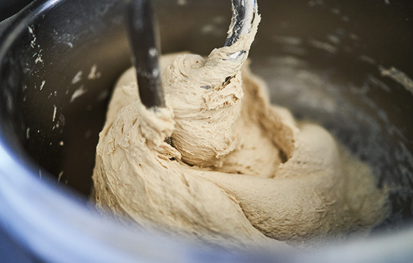 Masa en proceso de amasado en una amasadora profesional, vista desde el interior del recipiente de acero inoxidable.