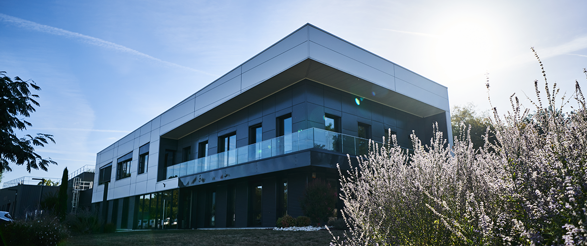 Façade extérieure des locaux de Philibert Savours à Crottet, bâtiment moderne avec balcon vitré entouré de végétation