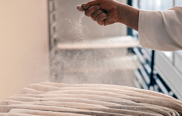A baker dusting his baguettes with flour