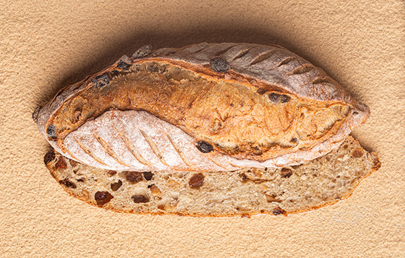 Apricot and raisin bread, cut in half lengthwise, placed on a bed of sourdough powder.