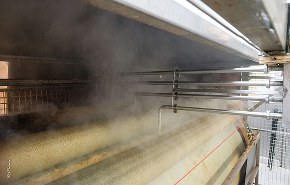 Instalación industrial con cilindros rotativos y vapor visible, en un entorno de producción.